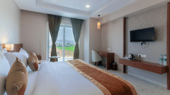 A double bed with a tv opposite it inside Super Deluxe room - VITS Satyajeet Karad