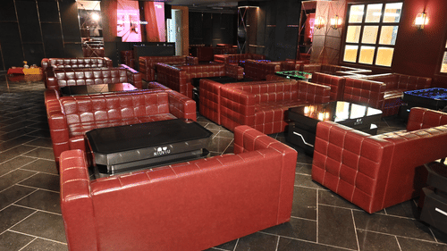 Spacious lounge area featuring red leather seating and modern interiors at Pride Elite Raipur.