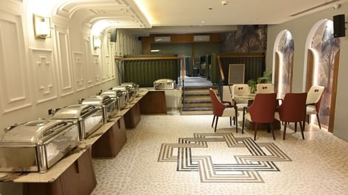Buffet setup with elegant chairs, patterned flooring, and bright interiors at Pride Elite Raipur.