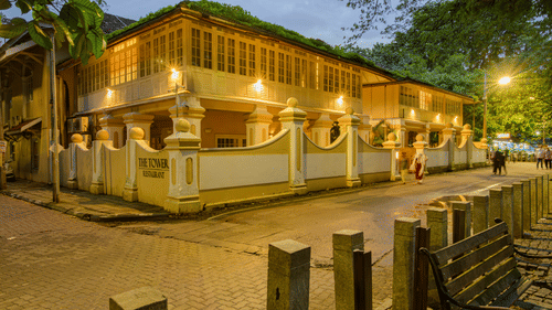 Facade of The Tower House - 17th Century, Cochin, in the dusk with lit up building and streets