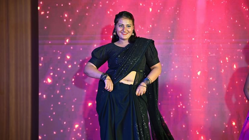 A picture featuring a lady posing with a screen in the background
