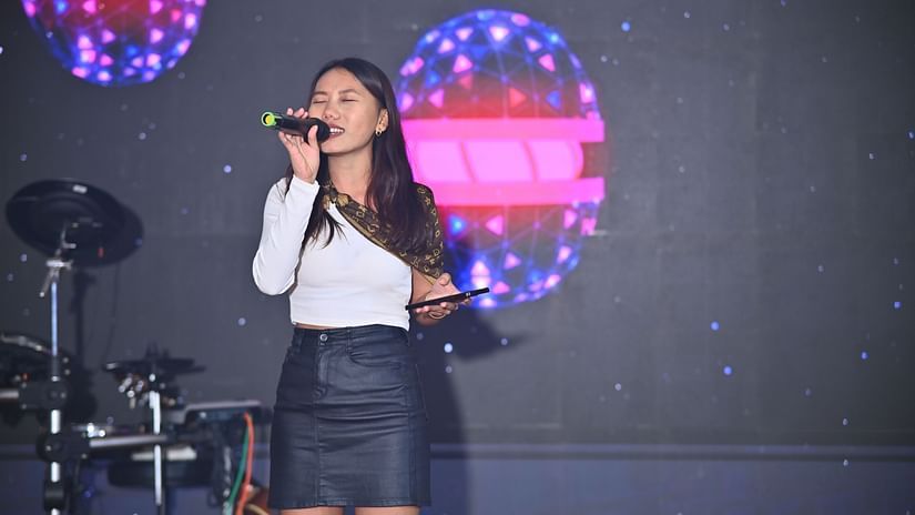 Picture featuring a lady singing with lights in the background