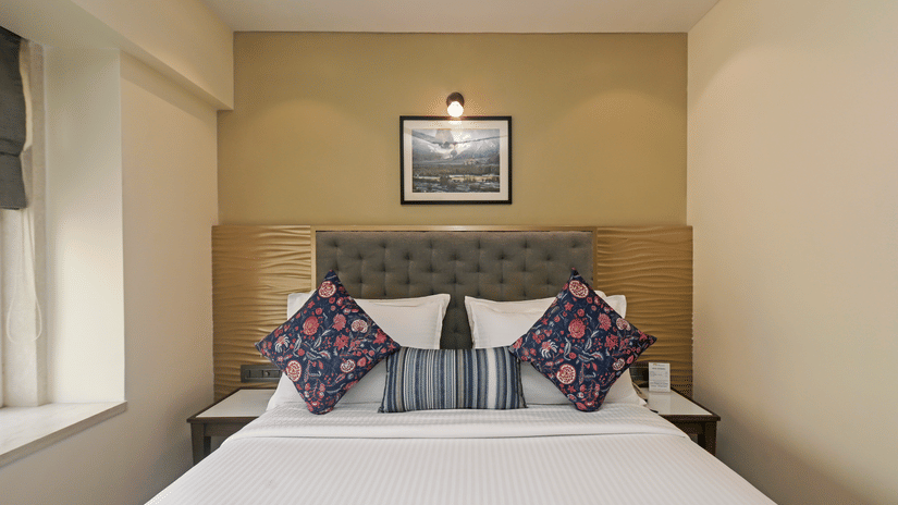Superior Room at Hotel Le Grande featuring a queen size bed, white duvet, and decorative blue and red pillows