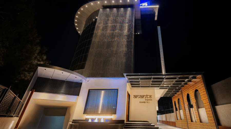 A low-angle shot of the modern hotel entrance illuminated with warm lights at night at Ananta Express, Katra.