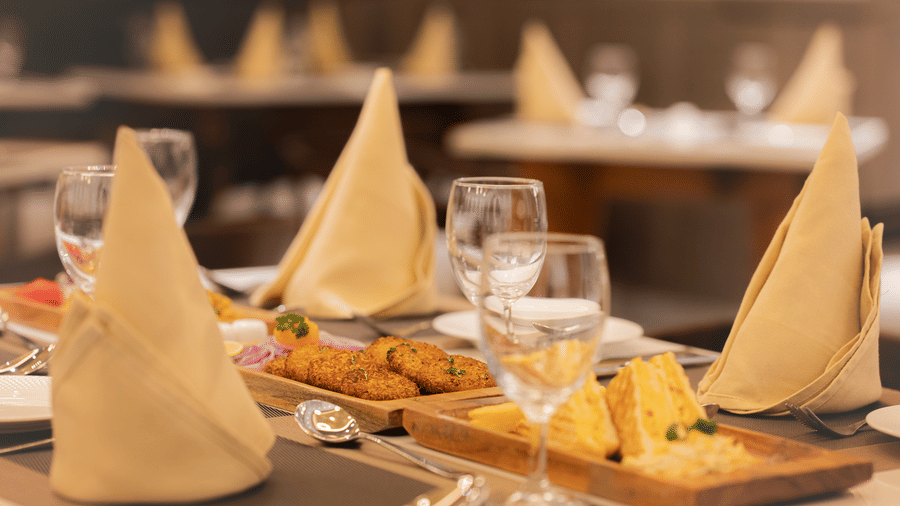 A close-up of a restaurant table set with beige napkins, glassware, and small appetisers at Ananta Express, Katra.