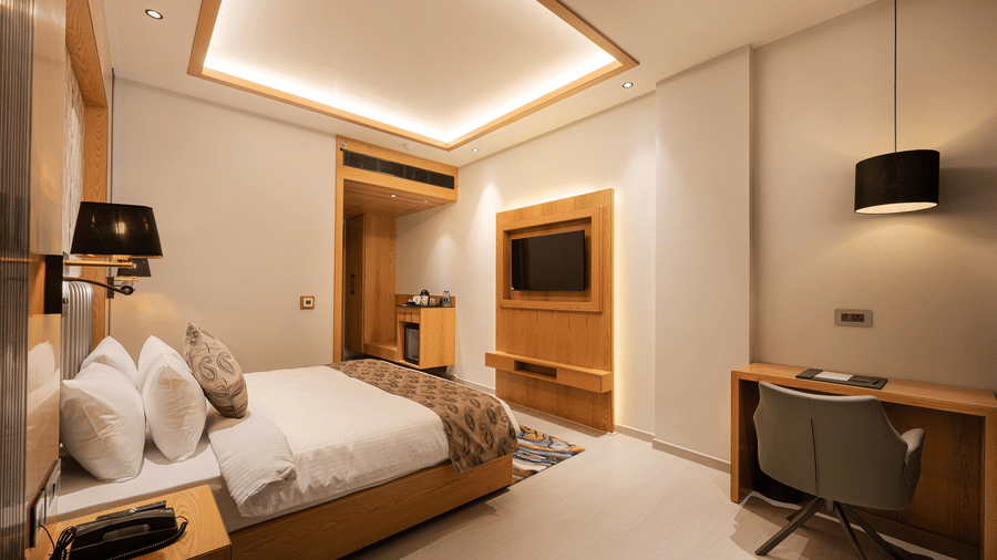 A modern guest room featuring a king-sized bed and a wooden wall unit with a mounted television at Ananta Express, Katra.