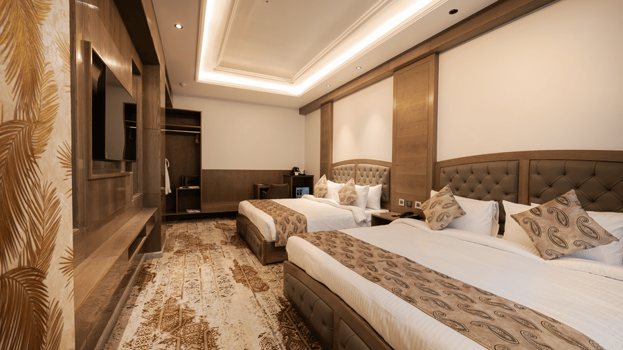 A guest room featuring two single beds with patterned headboards and modern wall-mounted television at Ananta Express, Katra.