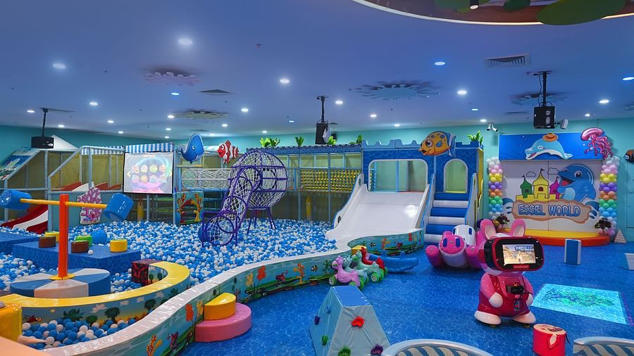 Indoor playground with colorful equipment, slides, and a ball pit, filled with children playing.