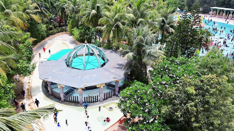 Aerial view of a circular pool with slides and a central structure, surrounded by trees.