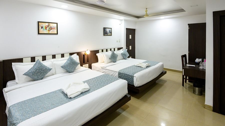 Side view of Deluxe Family Room featuring two cosy beds and wall lights at Biznotel by Pride, Deoghar.