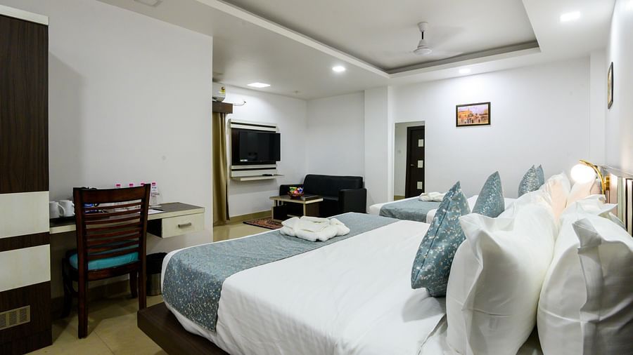 Side view of Deluxe Family Room featuring cozy beds and a TV mounted on the wall at Biznotel by Pride, Deoghar.