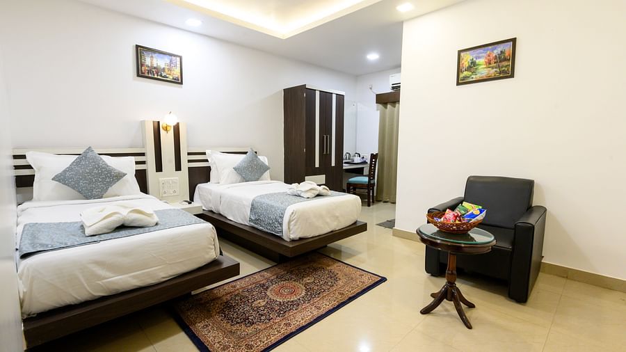 Deluxe Twin Room featuring two beds, a seating area, and modern decor at Biznotel by Pride, Deoghar