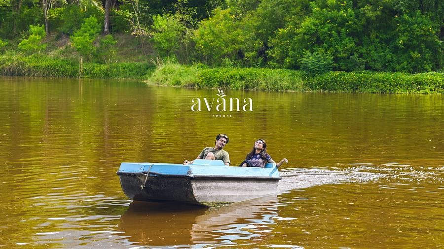 A small boat with people on a lake or river, surrounded by lush greenery.
