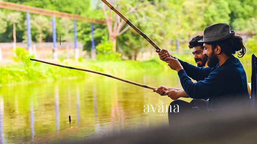 Two people fishing in a calm body of water, surrounded by greenery.