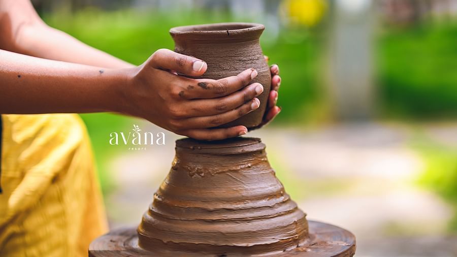 A close-up of hands shaping a clay pot on a pottery wheel.