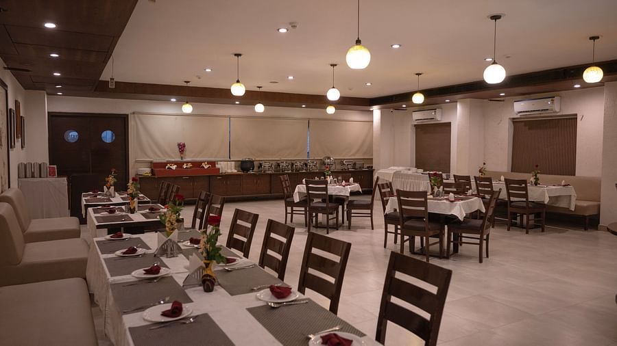 Clarks Collection Bhavnagar restaurant interior with arranged tables and warm lighting.
