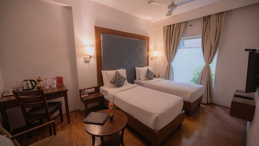 Warmly lit bedroom at Clarks Collection Bhavnagar with twin bed, desk, and chairs.