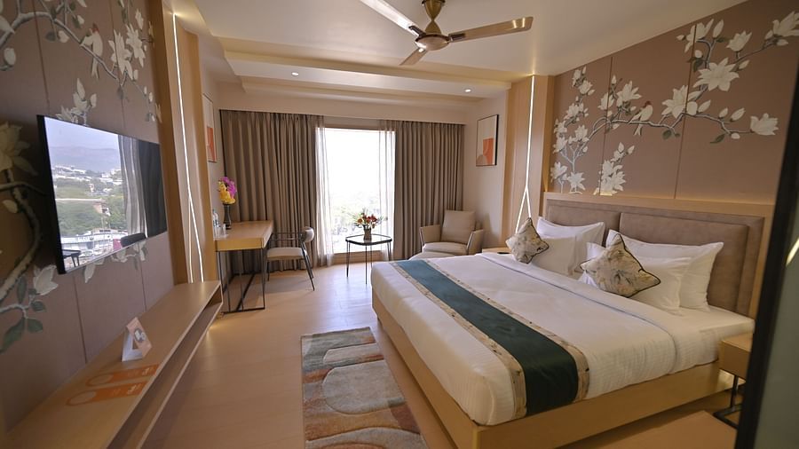 A bedroom with a ceiling fan and walls adorned with delicate flower paintings at  Clarks Collection Grand Sapphire, Ajmer.