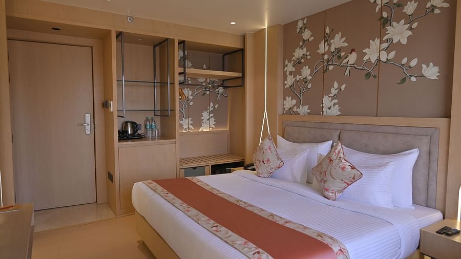 A side view of the Deluxe room with flower-painted walls, featuring a bed and elegant decor at Clarks Collection Grand Sapphire, Ajmer.