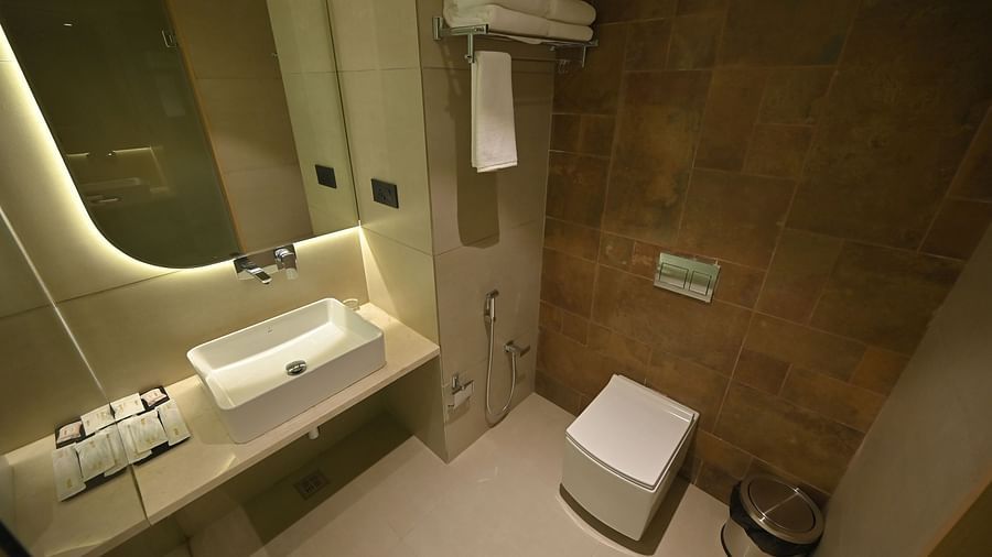 A modern bathroom featuring a sleek wash basin, large mirror, and warm yellow lights at Clarks Collection Grand Sapphire, Ajmer.