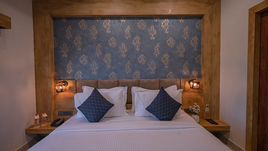 A double bed setup with floral headboard and bedside lamps at Clarks Collection, Somnath.