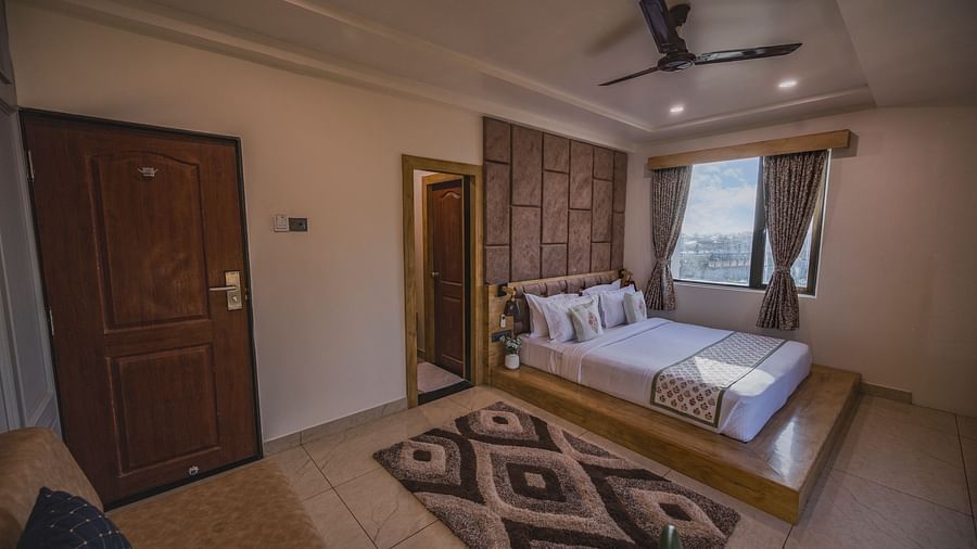 Clarks Collection Somnath room with double bed, wooden door, beige flooring, and windows with outside view.