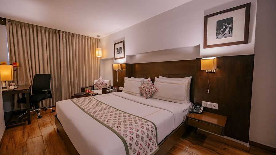 Twin beds with embroidered cushions, bedside phone, water bottles, and soft lighting at Clarks Collection Vadodara.