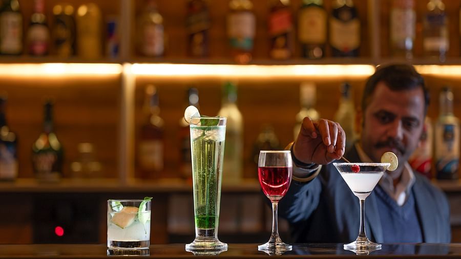 A well-lit hotel bar featuring a selection of bottles and drinks, with a bartender serving them - Clarks Inn Express, Near Jammu Bari Brahmana Railway Station