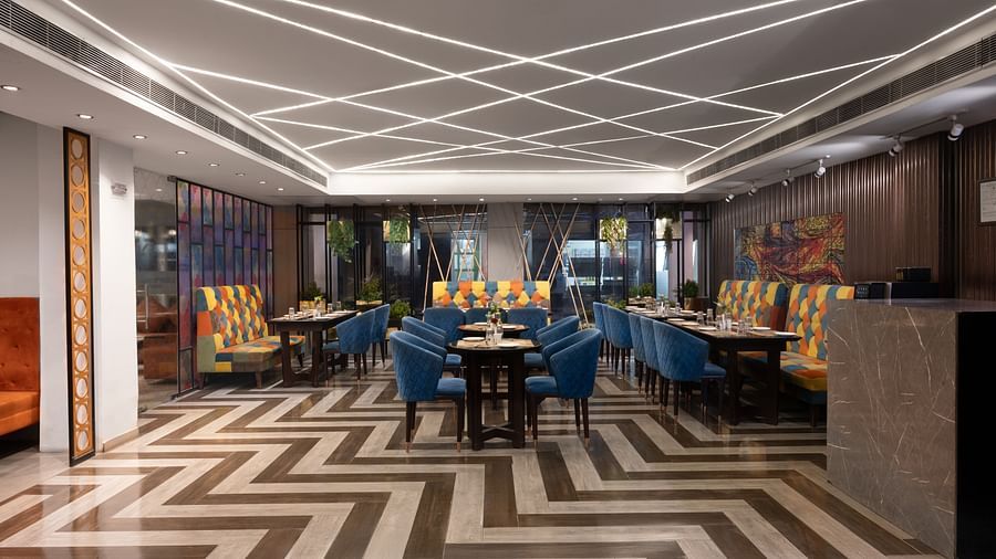 A stylish dining area featuring modern decor, with seating arranged and zigzag pattern on the floor - Clarks Inn Express, Near Jammu Bari Brahmana Railway Station