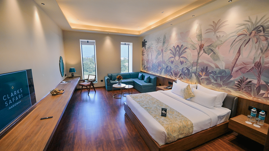 Premium Room featuring a king size bed, a seating area with a sofa, a large television, wooden flooring, and a mural on the wall.