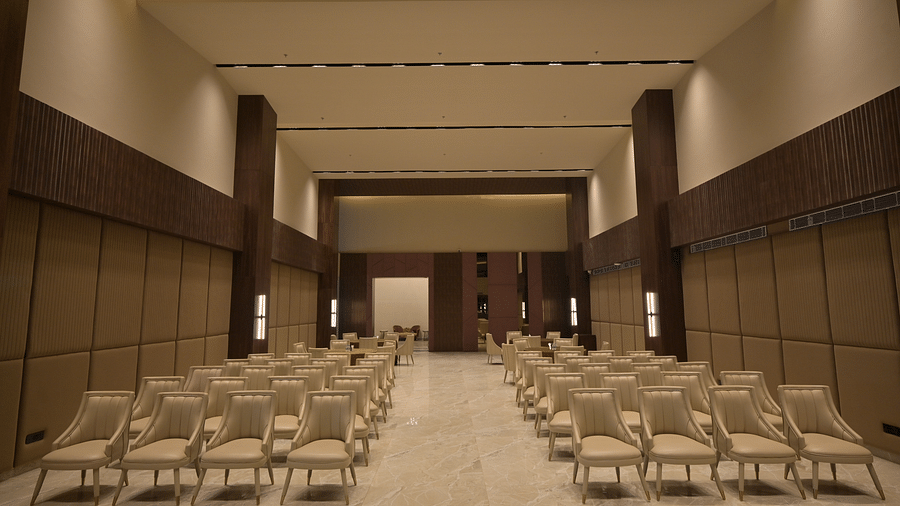 A large meeting room with rows of empty chairs facing a stage area. - Clarks Safari Haridwar