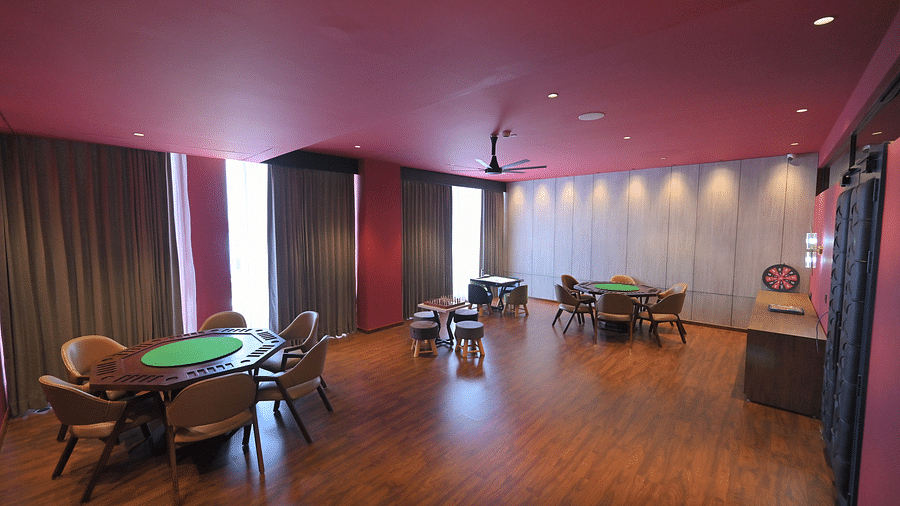 A brightly lit room features wooden floors, a pink ceiling, and several tables and chairs. - Clarks Safari Haridwar