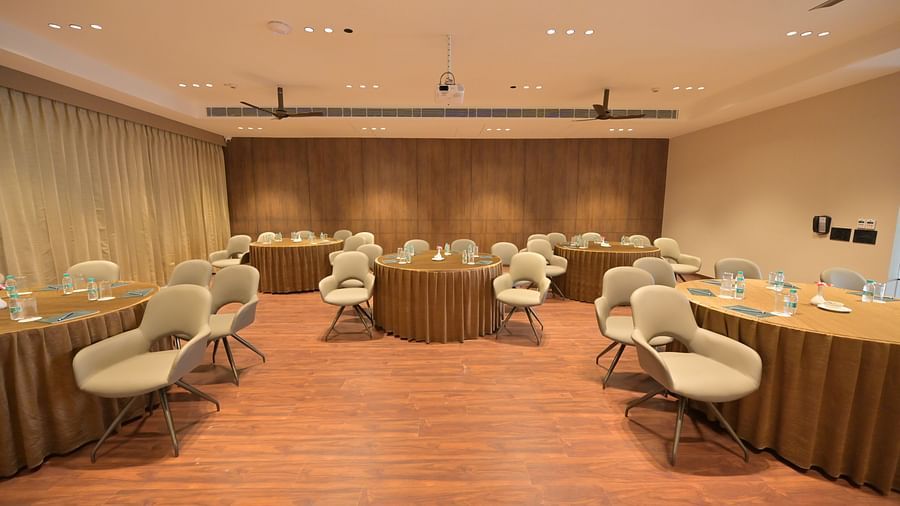 A well-lit meeting room with a U-shaped table arrangement, several chairs, and light wood flooring. - Clarks Safari Haridwar