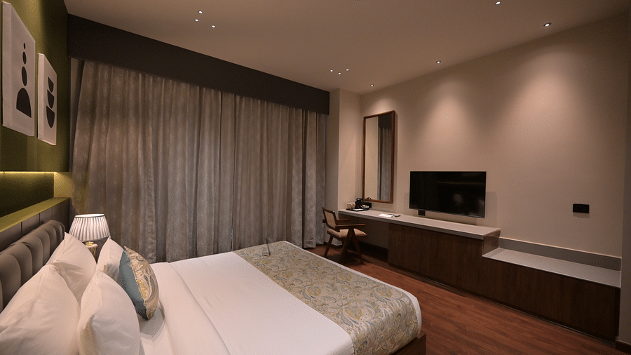 Deluxe Room features a neatly made bed, a TV, and neutral-toned decor. - Clarks Safari Haridwar