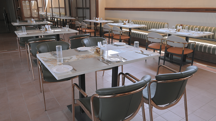 An interior of a restaurant dining area with tables and chairs set for service. - Clarks Safari Haridwar