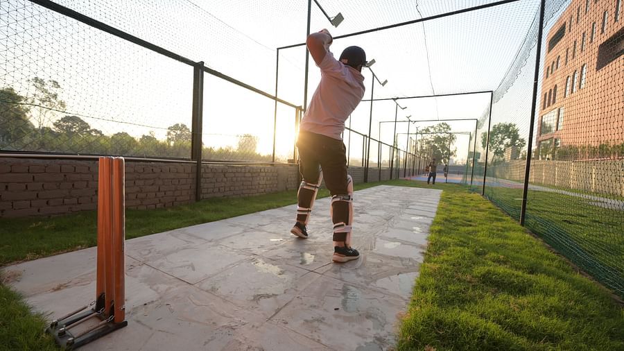 Two men playing cricket on a makeshift pitch, wearing cricket gear during the golden hour - Clarks Safari, Haridwar