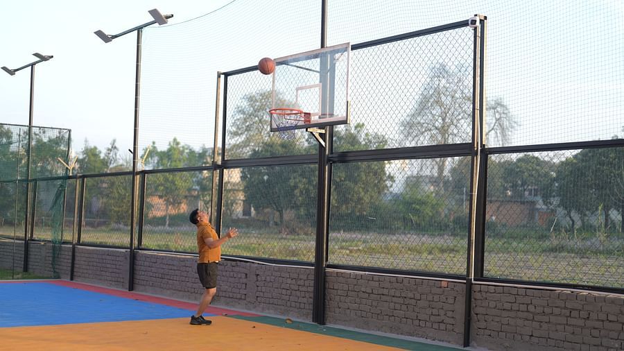 A guy playing basketball alone on a court, with lush greenery in the background - Clarks Safari, Haridwar