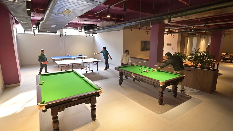 An arcade room with two snooker tables and two air hockey tables while some players are mid-match - Clarks Safari, Haridwar