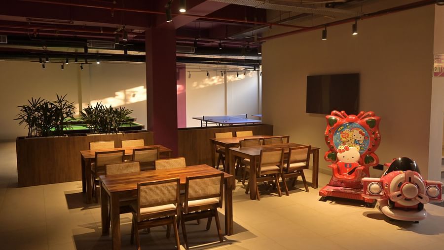 Three sets of chairs and tables arranged in a room, next to a huge Hello Kitty throne and a toy aeroplane for babies, with indoor plants and a ping pong table in the background - Clarks Safari, Haridwar