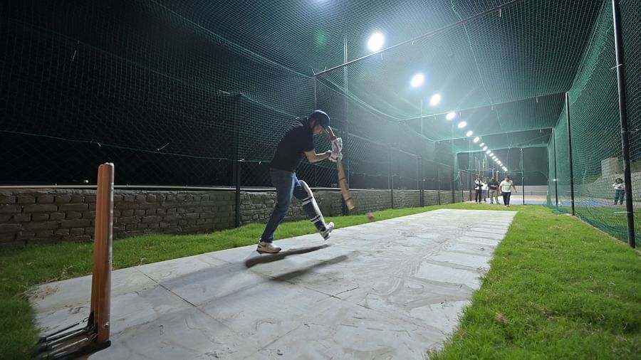 Two men playing cricket on a makeshift pitch, wearing cricket gear during the night - Clarks Safari, Haridwar