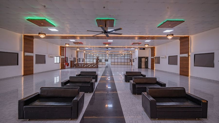 A long, open hall at Clarks Safari Kheda, set up with numerous seating arrangements, leading towards an exit.