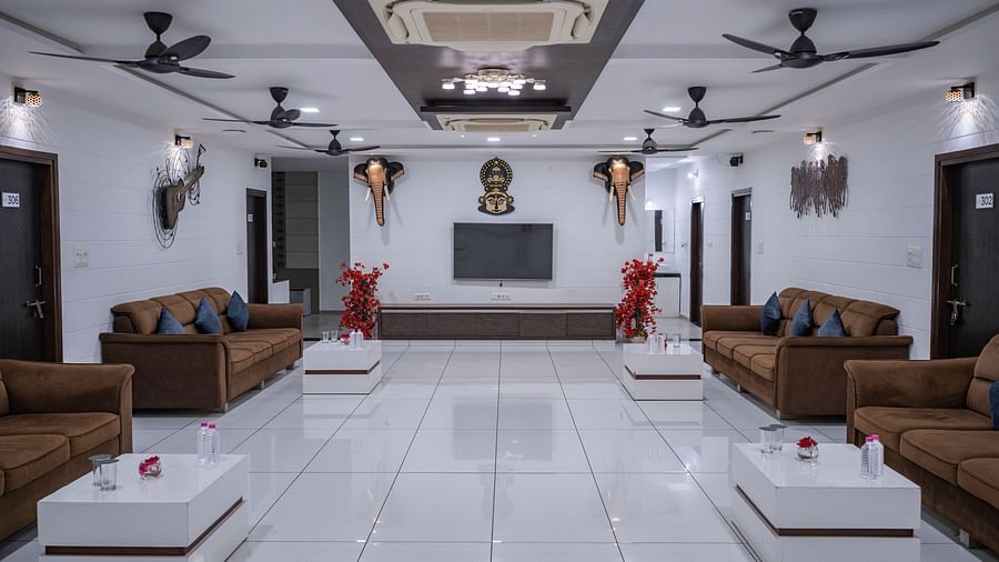 A lobby area at  Clarks Safari Kheda with a large, spacious room with rows of sofas and coffee tables arranged for seating, under multiple ceiling fans.
