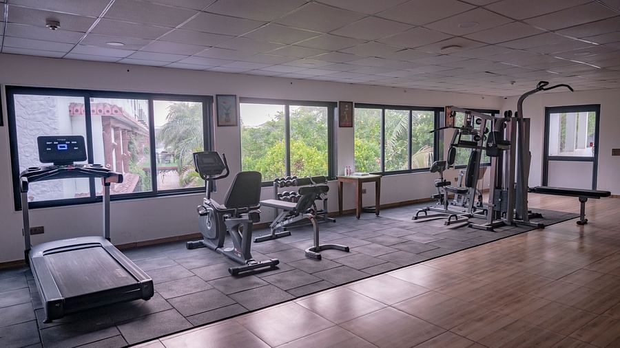 Inside Clarks Safari Kheda's gym, with various exercise machines like treadmills and weights, facing large window views.
