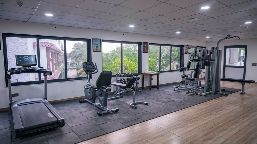 A wide view of Clarks Safari Kheda's gym, showing multiple workout stations and equipment spread across the floor, near windows.