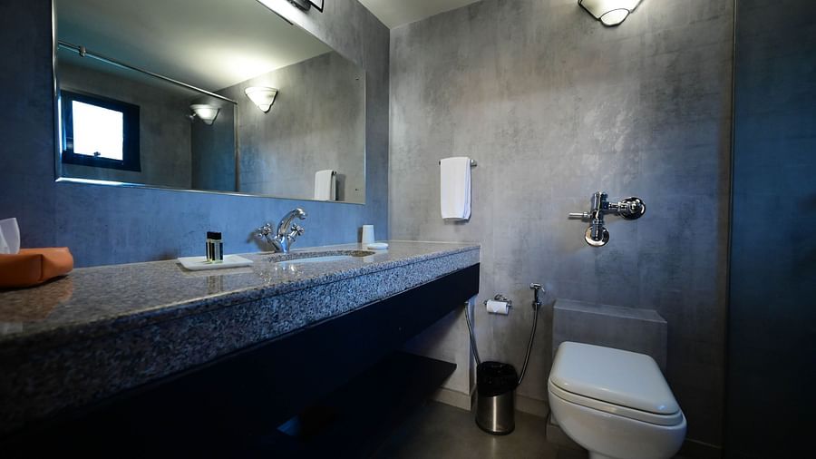 Bathroom of Deluxe Twin Cottage with blue walls and warm lighting featuring a large mirror over the sink and a toilet beside it