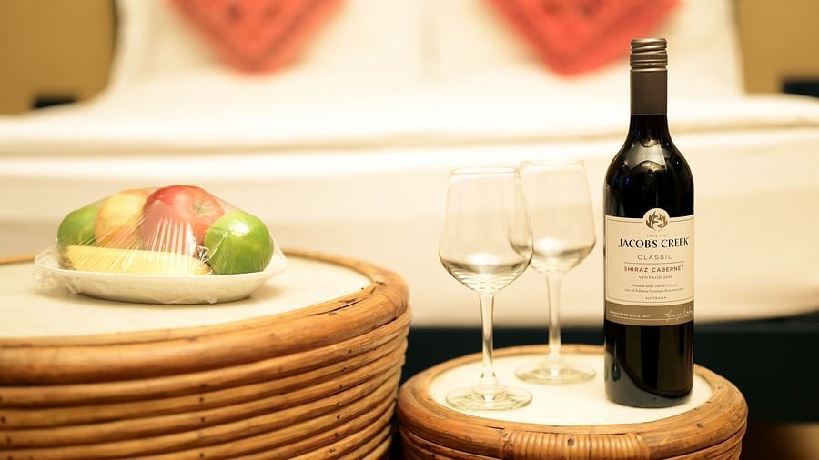 Fruits and wine with a couple of wine glasses placed in front of a plush bed in Superior Cottage at Clarks Safari, Pushkar