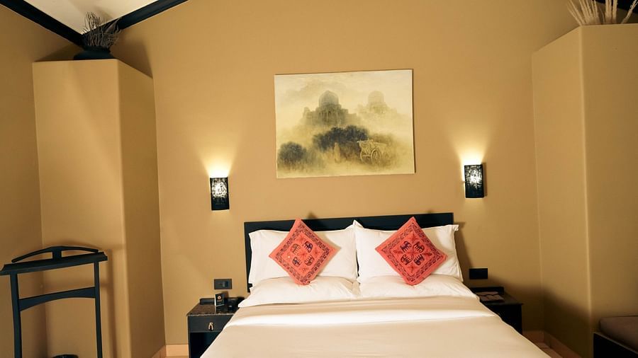 A plush bed with fresh linen and two lamps attached to the wall on both sides in Superior Cottage at Clarks Safari, Pushkar