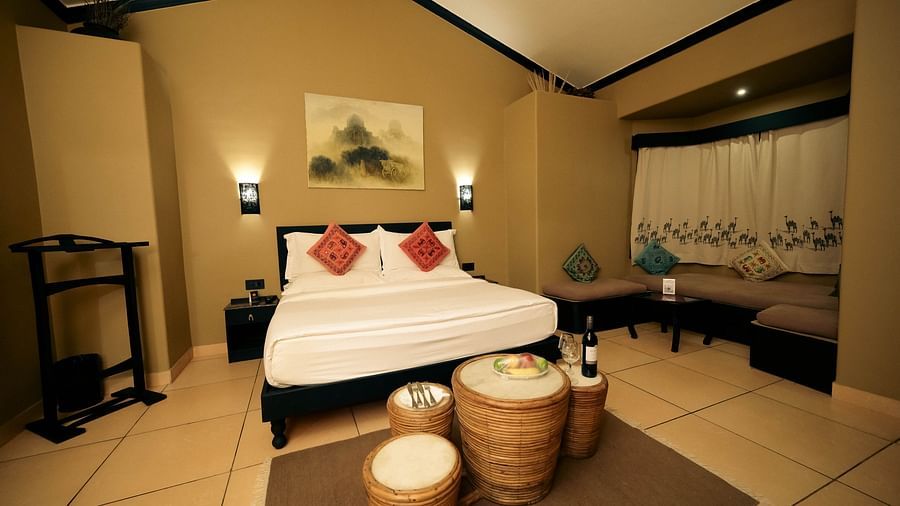 Superior Cottage at Clarks Safari, Pushkar featuring a plush bed near the cosy sitting space by the window and fruits and beverage placed in front of it