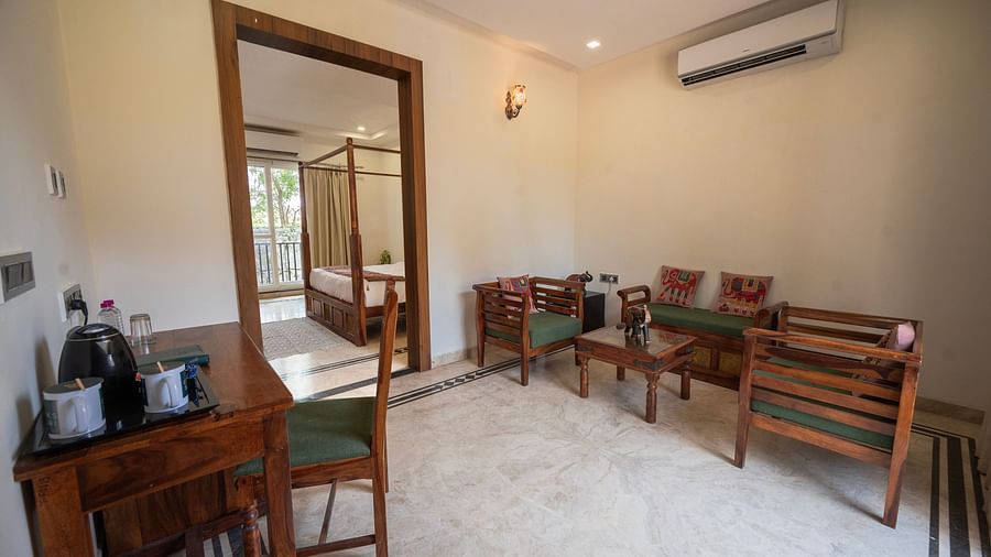 Modern living area with a wooden dining table and chairs, a mirrored wall reflecting the space, and a comfortable seating arrangement - Clarks Safari, Ranthambore