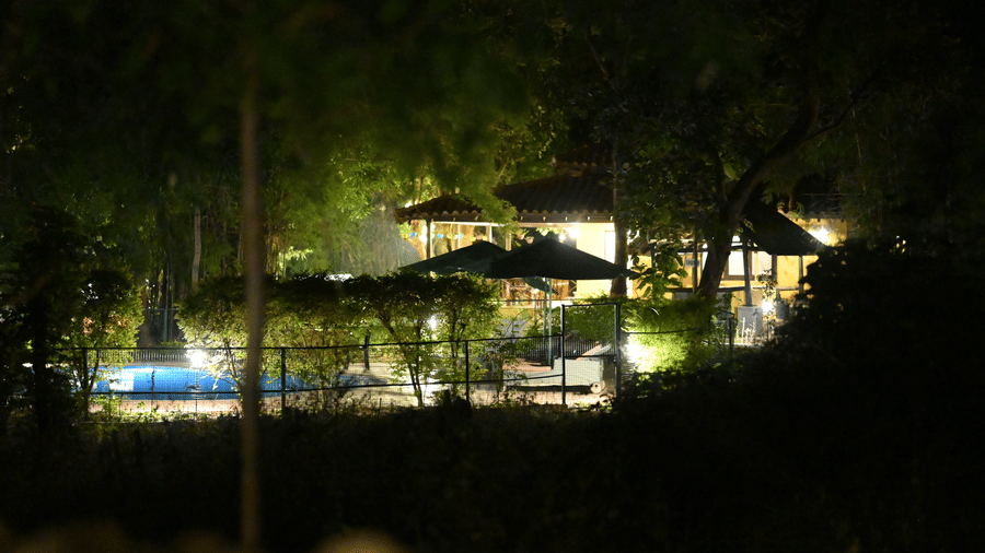 Outdoor night view showcasing a lit pathway, seating area, and surrounding trees within the resort premises at Infinity Resorts Bandhavgarh.